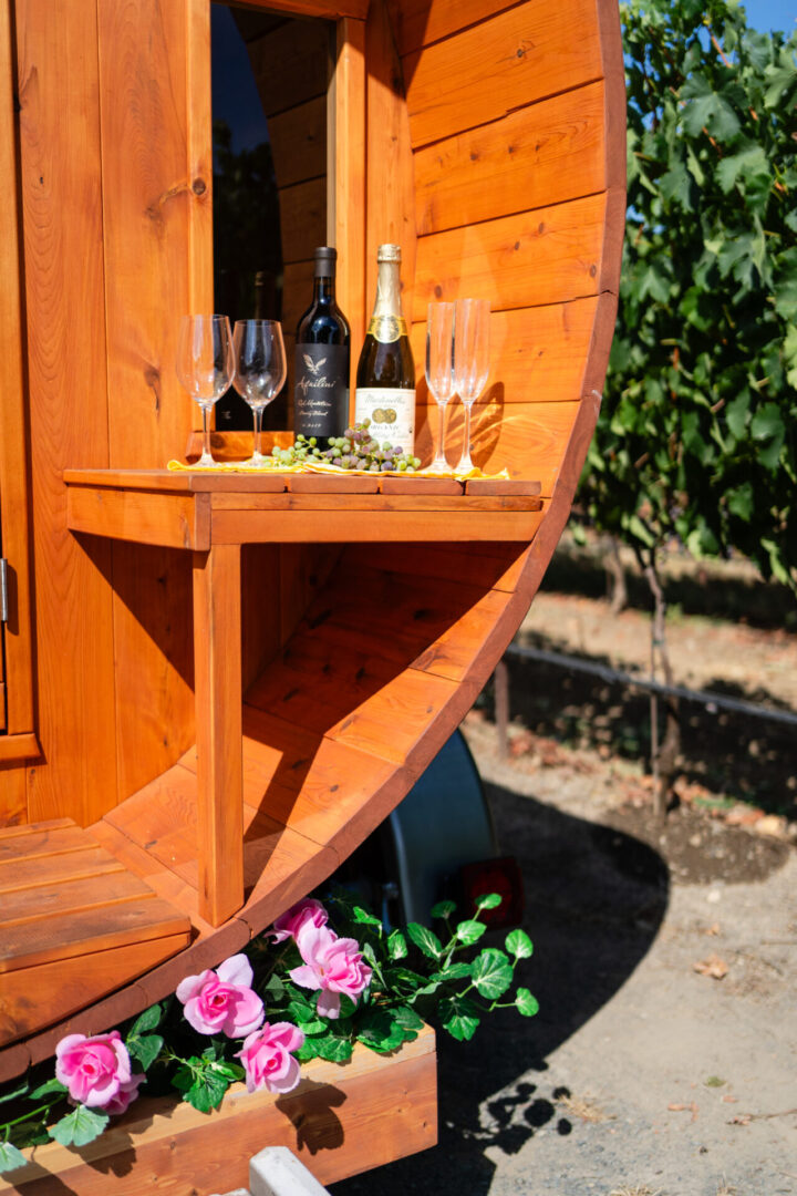 A wooden barrel with wine bottles and glasses on top of it.