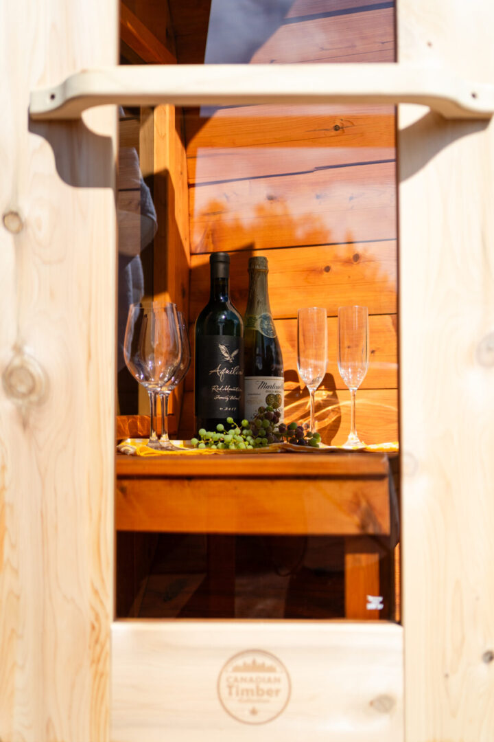 A wooden table with wine bottles and glasses on it.