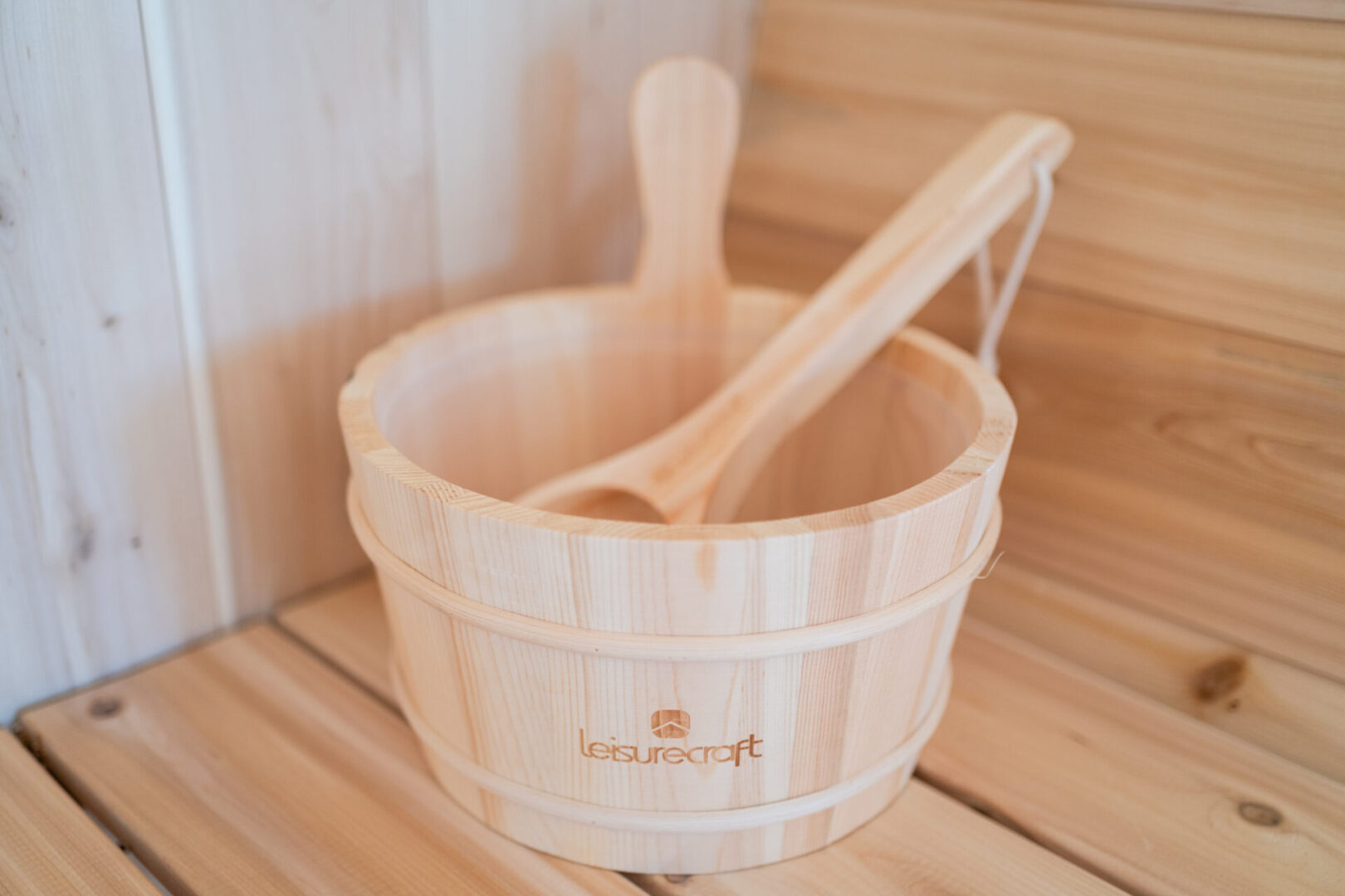 A wooden bucket and spoon sitting on top of a floor.