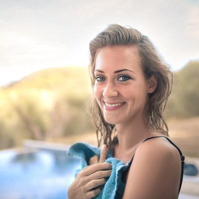 A woman holding onto some towels near the pool